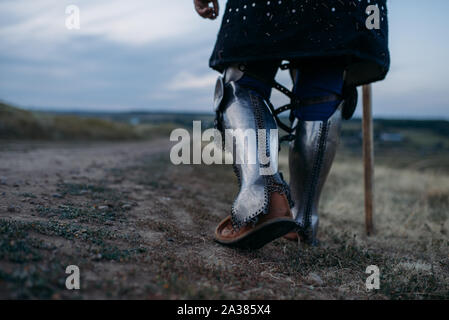 Medieval knight legs in metal armor, back view Stock Photo