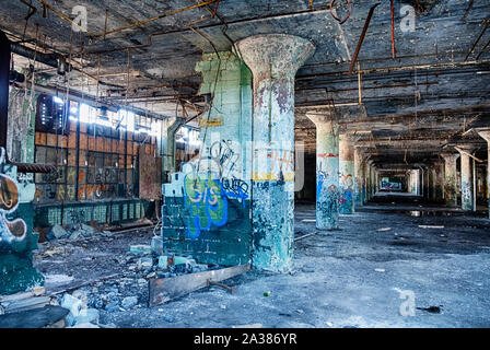 DETROIT, MICHIGAN - APRIL 28, 2019:  A view of the empty spaces within the Fisher Body Works plant in Detroit as seen from the outside through a broke Stock Photo