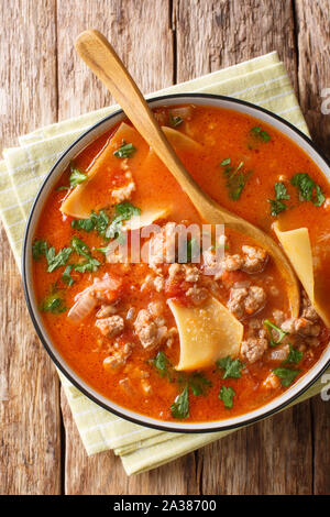 Tomato lasagna soup with minced meat closeup in a plate on the table. Vertical top view from above Stock Photo