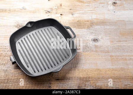 New empty cast-iron grill pan with two handles on a wooden background. place for text Stock Photo