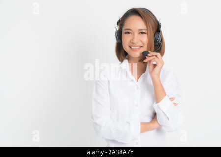 Portrait of happy smiling female customer support phone operator short hair, wearing a white shirt with headset standing one side holding the earphone Stock Photo