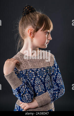 Portrait of a beautiful little schoolgirl on a dark background Stock Photo