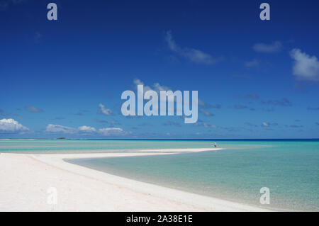 A man stands at the tip of a white sandy beach surrounded by a turquoise lagoon on the island of Fakarava, French Polynesia in the South Pacific Stock Photo