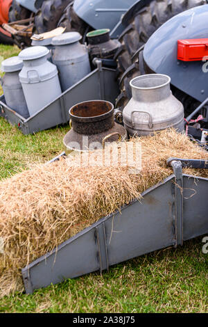 Milk churns and a bale of straw on the rear of a vintage tractor. Stock Photo