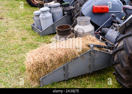 Milk churns and a bale of straw on the rear of a vintage tractor. Stock Photo