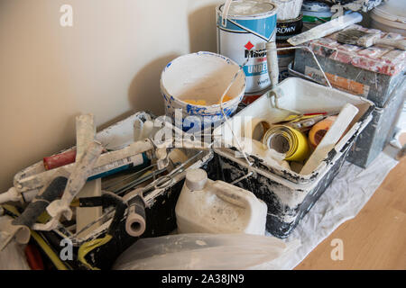 Tins of paint, brushes, rollers and other equipment in a room being decorated. Stock Photo
