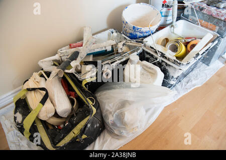 Tins of paint, brushes, rollers and other equipment in a room being decorated. Stock Photo