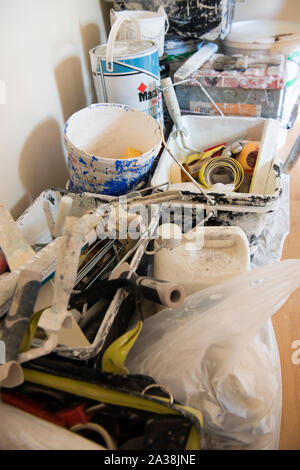 Tins of paint, brushes, rollers and other equipment in a room being decorated. Stock Photo