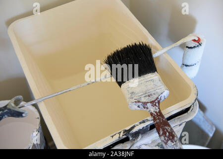 Tins of paint, brushes, rollers and other equipment in a room being decorated. Stock Photo