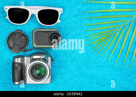 Sunglasses, extreme camera, camera, fern lie on a towel. Stock Photo