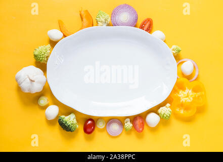 Vegetables with a white plate on yellow background Stock Photo