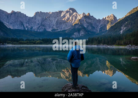 traveler admiring the alpine lake during sunrise Stock Photo