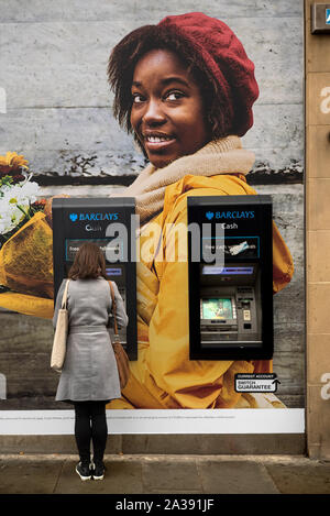 Young woman customer using a Barclays Bank ATM on Princes Street in Edinburgh, Scotland, UK. Stock Photo