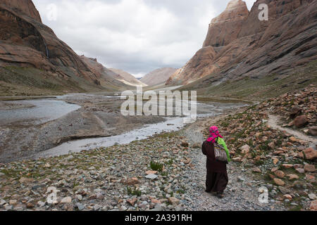 A pilgrim walks into Lha-chu valley on the path around Mount Kailash in Tibet - one of the most important pilgrimage routes for Buddhists and Hindus. Stock Photo