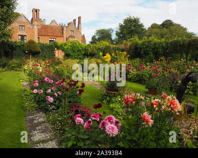 Chenies Manor Sunken garden on a September evening looking towards the Tudor house through the mass planting of colourful dahlias, path and trellis. Stock Photo