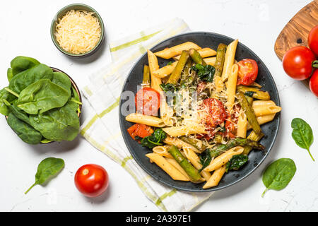 Vegan pasta penne with spinach, asparagus and tomato. Stock Photo