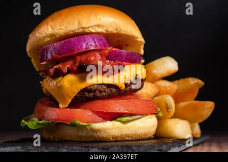Bacon Cheeseburger with Lettuce Tomato Onion on a Dark Background and Brioche bun Stock Photo