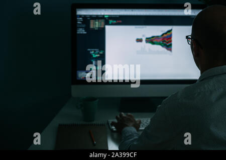 Developer, working behind the desk, analysing diagram on the monitor Stock Photo