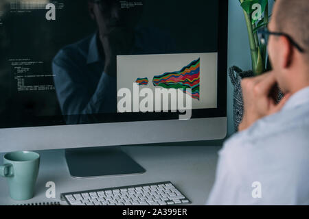 Developer, working behind the desk, analysing diagram on the monitor Stock Photo
