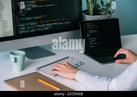 Programmer, working behind the desk, analysing code on the black screen. Stock Photo