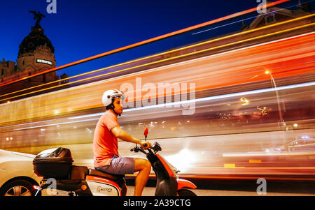 Madrid, Spain - Oct 5, 2019: Young man on a vespa waiting for traffic to pass at the busy dangerous intersection of Calle de Alcala and Gran Via Stock Photo