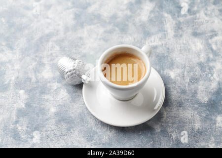Cup of coffee and silver Christmas bauble on bright wooden background. Copy space. Stock Photo