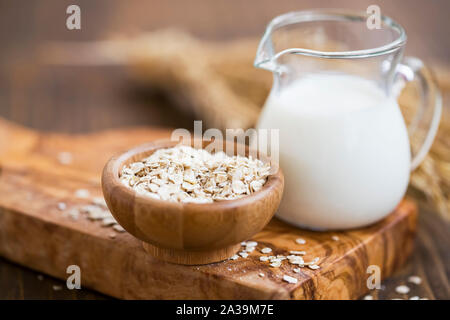 Oat milk, vegan alternative for diary milk, healthy vegetal milk with oat flakes bowl Stock Photo