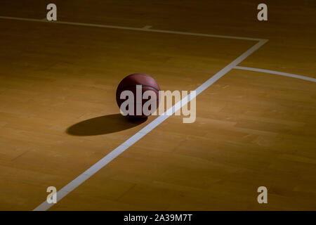 Basketball On Hardwood Court Floor With Spot Lighting Stock Photo