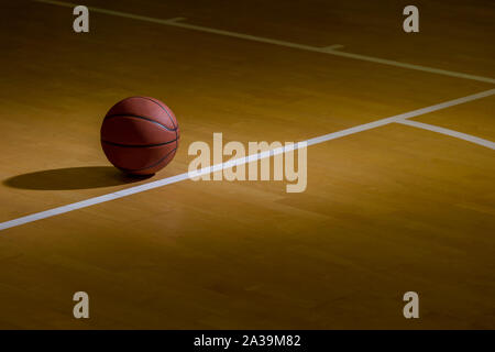Basketball On Hardwood Court Floor With Spot Lighting Stock Photo