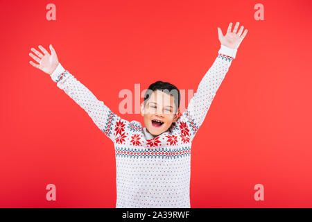 front view of excited child in sweater isolated on red Stock Photo