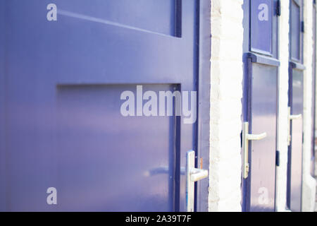 Close up of blue doors against white brick wall at a train station. Stock Photo