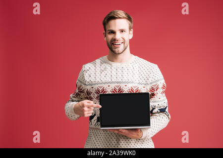 handsome man pointing at laptop with blank screen isolated on red Stock Photo
