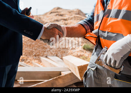 cropped view of constructor and businessman shaking hands Stock Photo
