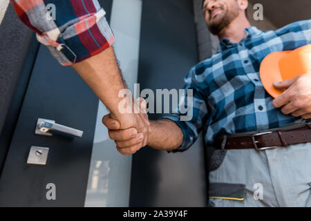 cropped view of men shaking hands while standing near door Stock Photo