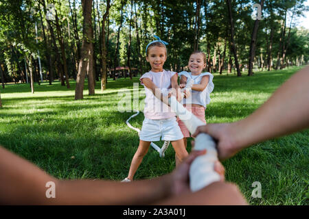 selective focus of cheerful multicultural children competing in tug of war outside Stock Photo