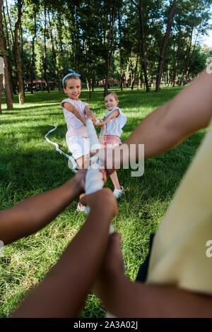 cropped view of multicultural children competing in tug of war with cute friends outside Stock Photo