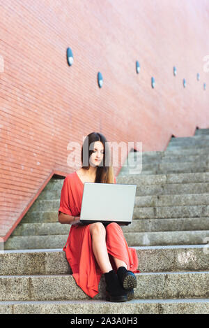 Beautiful young woman using laptop on stairs Stock Photo