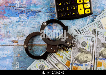 Crime accounting financial with calculator and police handcuffs on hundred dollar bills money pile Stock Photo