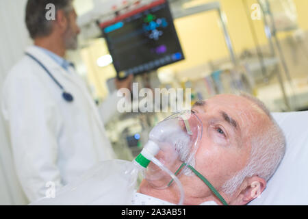 man lying in hospital bed getting oxygen in intensive-care-unit Stock Photo