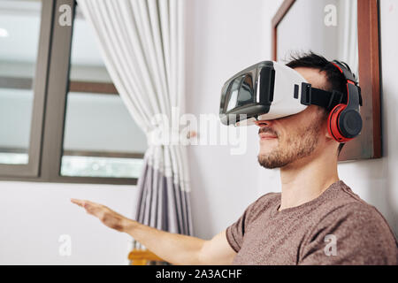 Positive young man wearing VR headset when testing new application he created Stock Photo