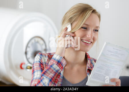 plumber on the phone checking instructions of boiler Stock Photo