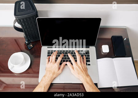 Student programming on laptop. Opened textbook, cup of coffee, speaker and vape on his desk Stock Photo