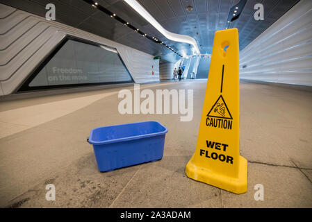 A bucket and a wet floor sign provide a different view of the relatively new Wynyard Walk pedestrian tunnel during a period of heavy rain in Sydney. Stock Photo