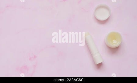 Top view of a tube of white lip balm and a small round container of solid perfume. Stock Photo