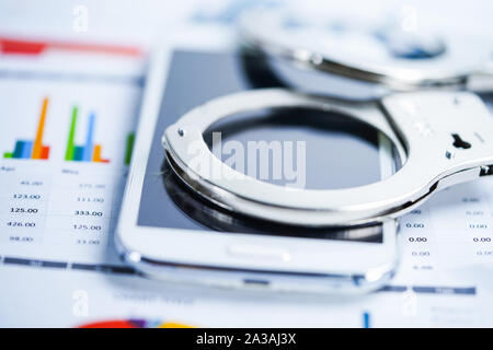 Metal handcuffs and mobile phone on chart graph background. Hacker economy finance banking static concept. Stock Photo