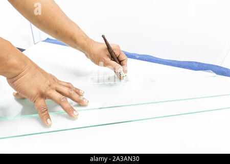 Close up glazier are cutting glass. Technicians is using the glass cutting tool. Stock Photo