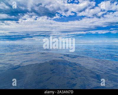 Cloudy sky reflected on calm blue water Stock Photo