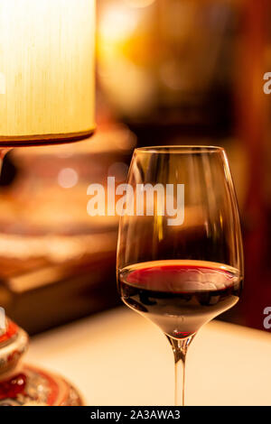 Red wine glass under table lamp Stock Photo