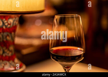 Red wine glass under table lamp Stock Photo