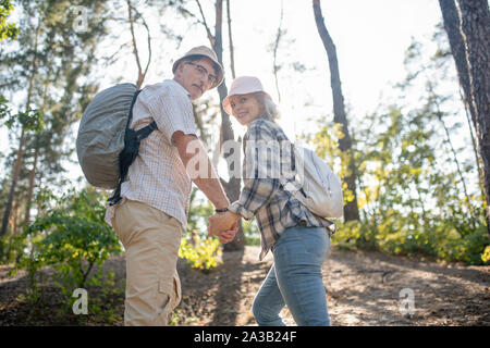 Beaming couple wearing backpacks enjoying their day off Stock Photo